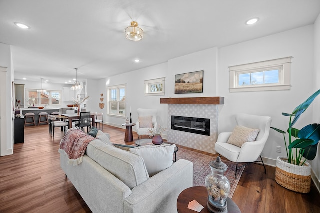 living room featuring hardwood / wood-style flooring, a chandelier, and a tiled fireplace