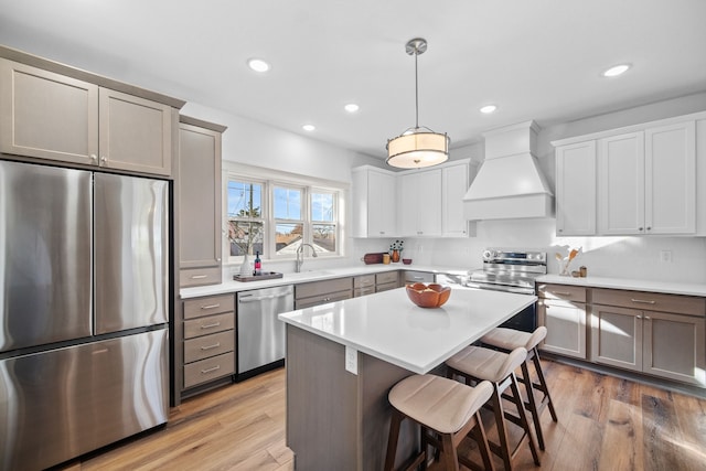 kitchen featuring pendant lighting, wood-type flooring, stainless steel appliances, and custom exhaust hood