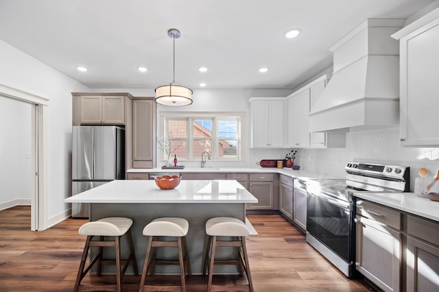 kitchen with stainless steel appliances, premium range hood, pendant lighting, gray cabinets, and light wood-type flooring