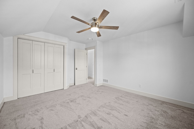 unfurnished bedroom with carpet floors, a closet, vaulted ceiling, and ceiling fan