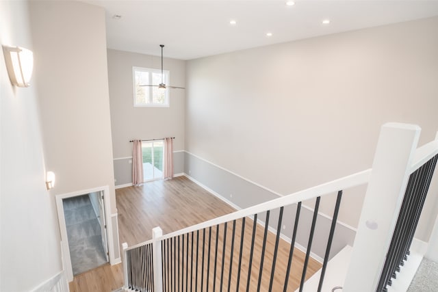 stairs featuring wood-type flooring and ceiling fan