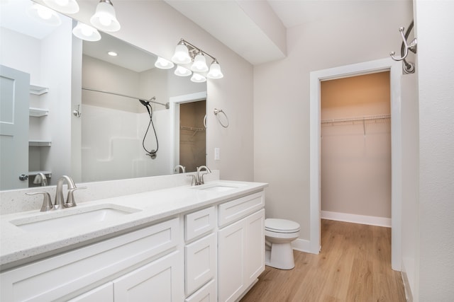 bathroom featuring hardwood / wood-style floors, vanity, toilet, and walk in shower