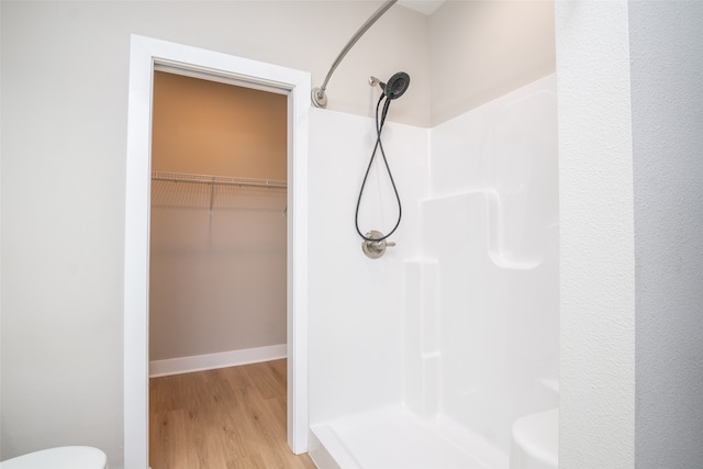 bathroom featuring hardwood / wood-style flooring, toilet, and walk in shower