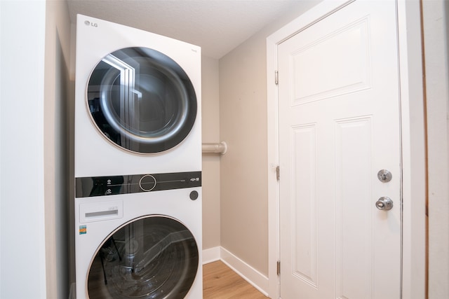 laundry room with light hardwood / wood-style flooring and stacked washing maching and dryer