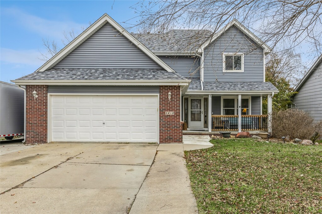 view of front of home featuring a porch, a garage, and a front lawn