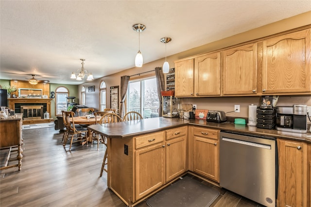 kitchen featuring kitchen peninsula, appliances with stainless steel finishes, dark hardwood / wood-style flooring, a breakfast bar, and decorative light fixtures