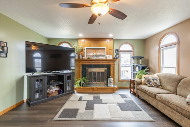 living room with a fireplace, a textured ceiling, dark hardwood / wood-style flooring, and ceiling fan