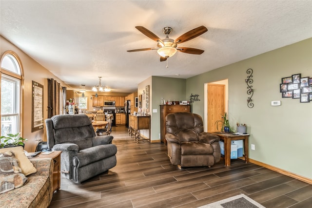 living room with dark hardwood / wood-style flooring, ceiling fan with notable chandelier, and a textured ceiling