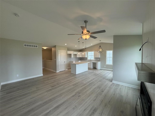 unfurnished living room featuring ceiling fan, light hardwood / wood-style flooring, and vaulted ceiling