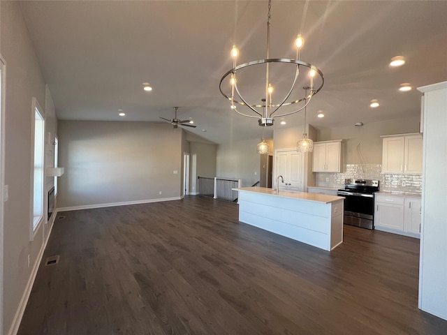 kitchen featuring a center island with sink, decorative backsplash, electric stove, ceiling fan with notable chandelier, and white cabinets