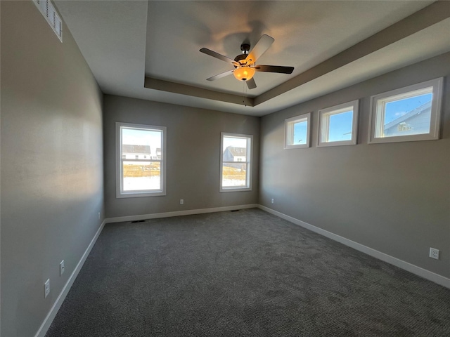 carpeted spare room featuring a raised ceiling and ceiling fan