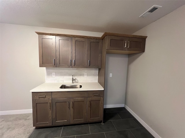 kitchen featuring dark tile patterned floors, backsplash, and sink