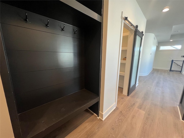 mudroom with light wood-type flooring and a barn door