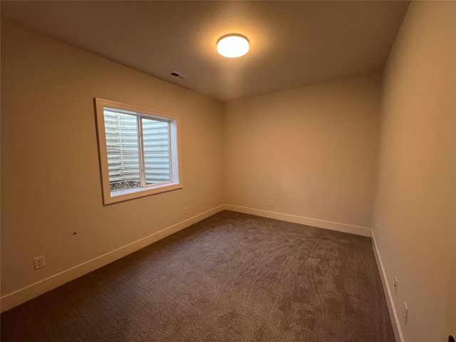 spare room with dark colored carpet