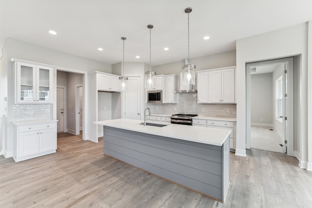 kitchen with white cabinets, a center island with sink, sink, and appliances with stainless steel finishes