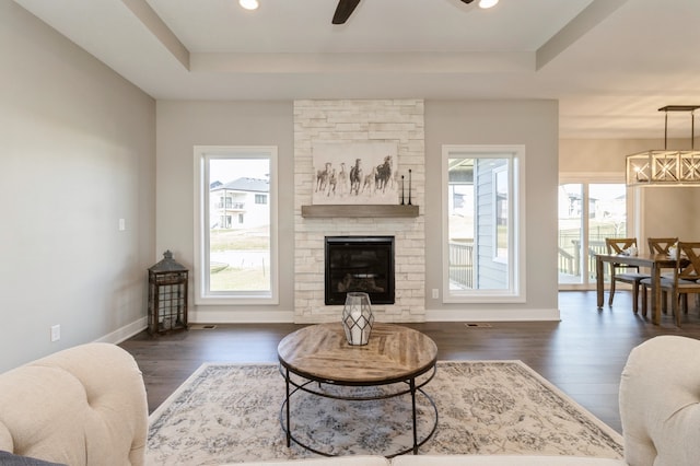 living room featuring ceiling fan, a healthy amount of sunlight, dark hardwood / wood-style flooring, and a fireplace