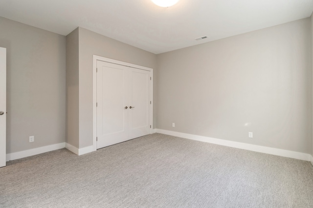 unfurnished bedroom featuring light carpet and a closet