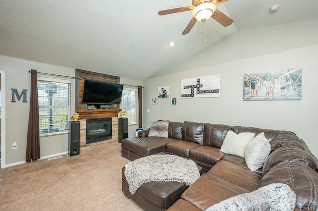 living room featuring ceiling fan, a large fireplace, light colored carpet, a textured ceiling, and lofted ceiling