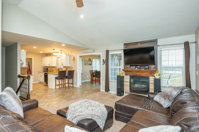 living room featuring a textured ceiling, a large fireplace, ceiling fan, and lofted ceiling