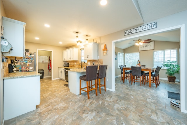 kitchen featuring white cabinetry, ceiling fan, kitchen peninsula, vaulted ceiling, and decorative backsplash