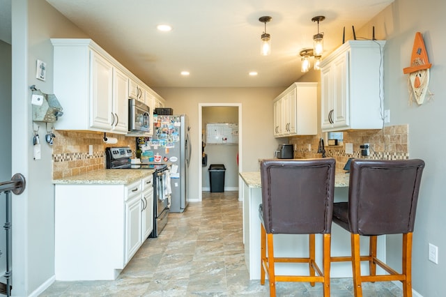 kitchen with light stone counters, white cabinetry, stainless steel appliances, and decorative light fixtures