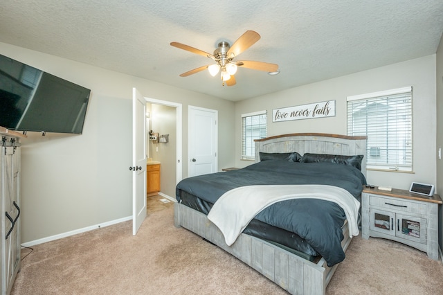 carpeted bedroom featuring a textured ceiling, ensuite bathroom, and ceiling fan