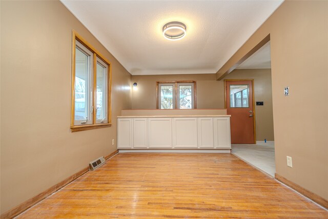 unfurnished room with a textured ceiling and light wood-type flooring