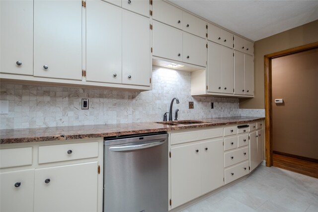 kitchen with light stone countertops, backsplash, stainless steel dishwasher, sink, and white cabinets