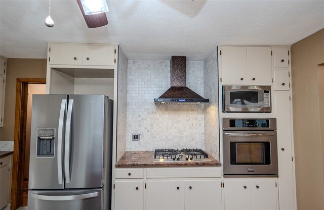 kitchen with white cabinets, wall chimney range hood, and stainless steel appliances