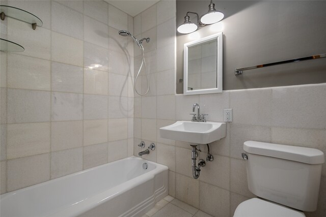 full bathroom featuring sink, tiled shower / bath combo, tile patterned flooring, toilet, and tile walls