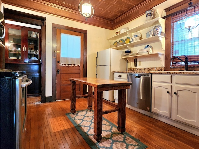 kitchen with pendant lighting, hardwood / wood-style floors, white cabinets, crown molding, and stainless steel appliances