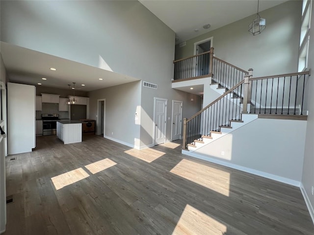 unfurnished living room featuring dark hardwood / wood-style flooring and a towering ceiling