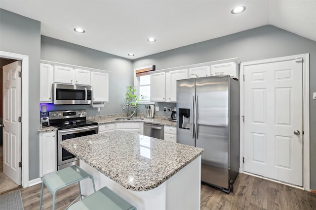 kitchen with sink, lofted ceiling, a breakfast bar area, a kitchen island, and appliances with stainless steel finishes