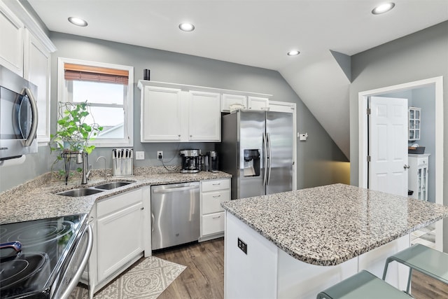 kitchen featuring appliances with stainless steel finishes, a center island, white cabinetry, and a kitchen breakfast bar