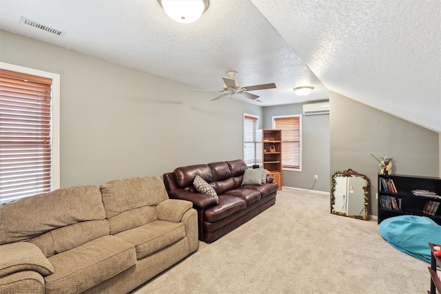 living room with ceiling fan, an AC wall unit, vaulted ceiling, a textured ceiling, and light carpet