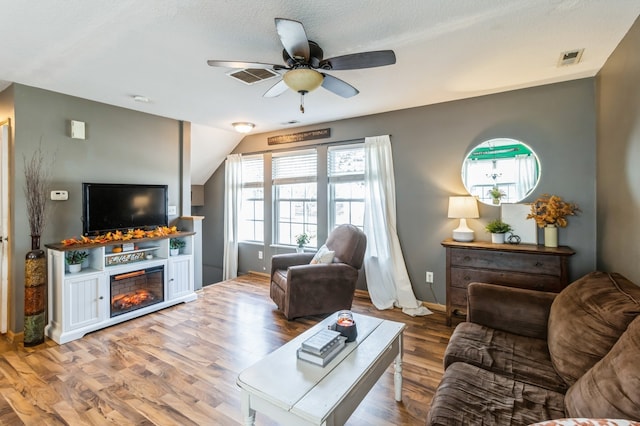 living room with a healthy amount of sunlight, wood-type flooring, and vaulted ceiling