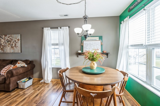 dining space with hardwood / wood-style floors and a notable chandelier