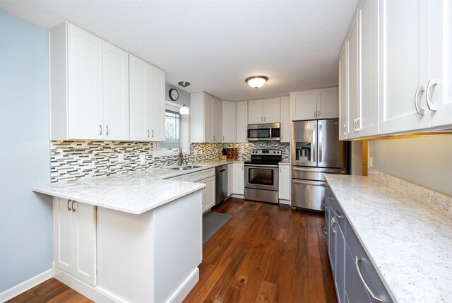 kitchen featuring light stone countertops, dark hardwood / wood-style flooring, white cabinets, and stainless steel appliances