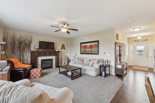 living room featuring a tile fireplace, ceiling fan, and dark hardwood / wood-style flooring