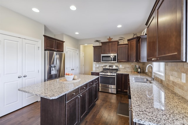 kitchen featuring sink, dark hardwood / wood-style floors, light stone countertops, appliances with stainless steel finishes, and a kitchen island