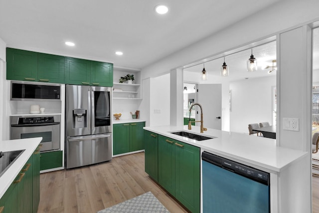 kitchen with sink, green cabinetry, light wood-type flooring, appliances with stainless steel finishes, and decorative light fixtures