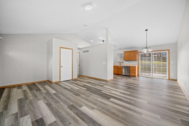 unfurnished living room featuring a chandelier, vaulted ceiling, and light wood-type flooring