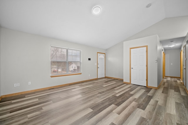 unfurnished living room featuring lofted ceiling, baseboards, and wood finished floors