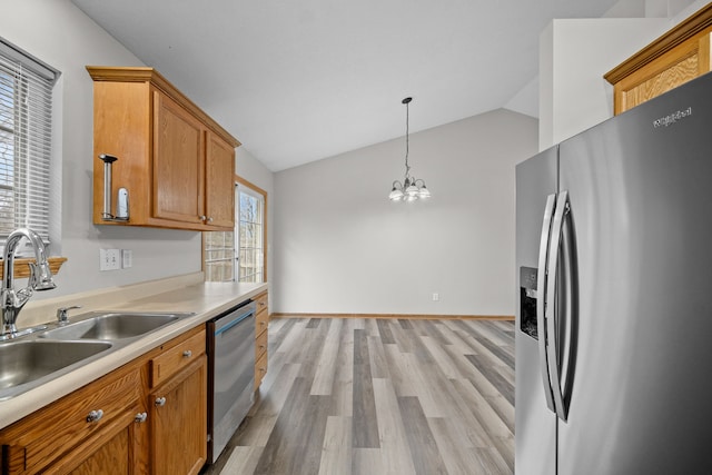 kitchen with stainless steel appliances, a sink, vaulted ceiling, light countertops, and light wood-type flooring