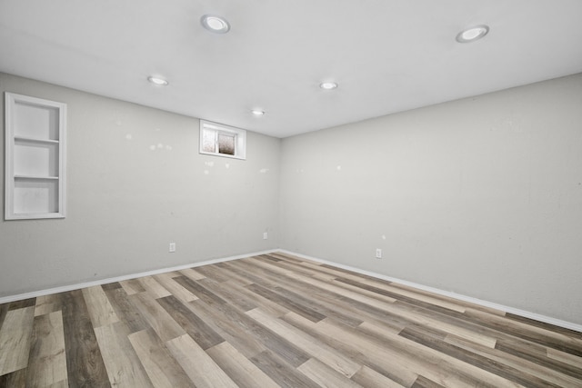 spare room with built in shelves, recessed lighting, baseboards, and wood finished floors