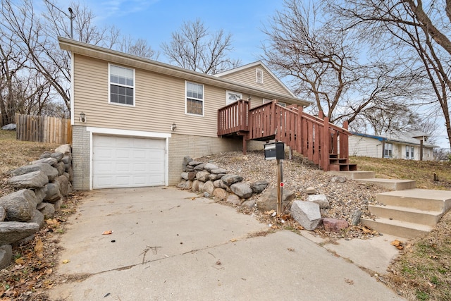 view of front of property with an attached garage, brick siding, fence, stairs, and concrete driveway