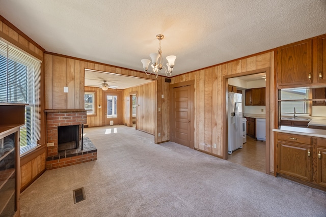 carpeted living room featuring a brick fireplace, plenty of natural light, and wood walls