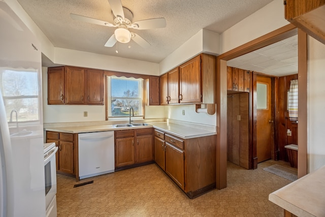 kitchen featuring a textured ceiling, white appliances, ceiling fan, and sink