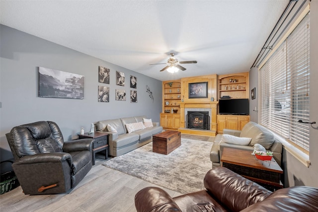 living room featuring light hardwood / wood-style floors, ceiling fan, and built in shelves