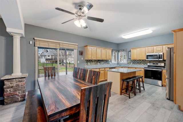 dining room with a textured ceiling, light hardwood / wood-style flooring, decorative columns, ceiling fan, and sink